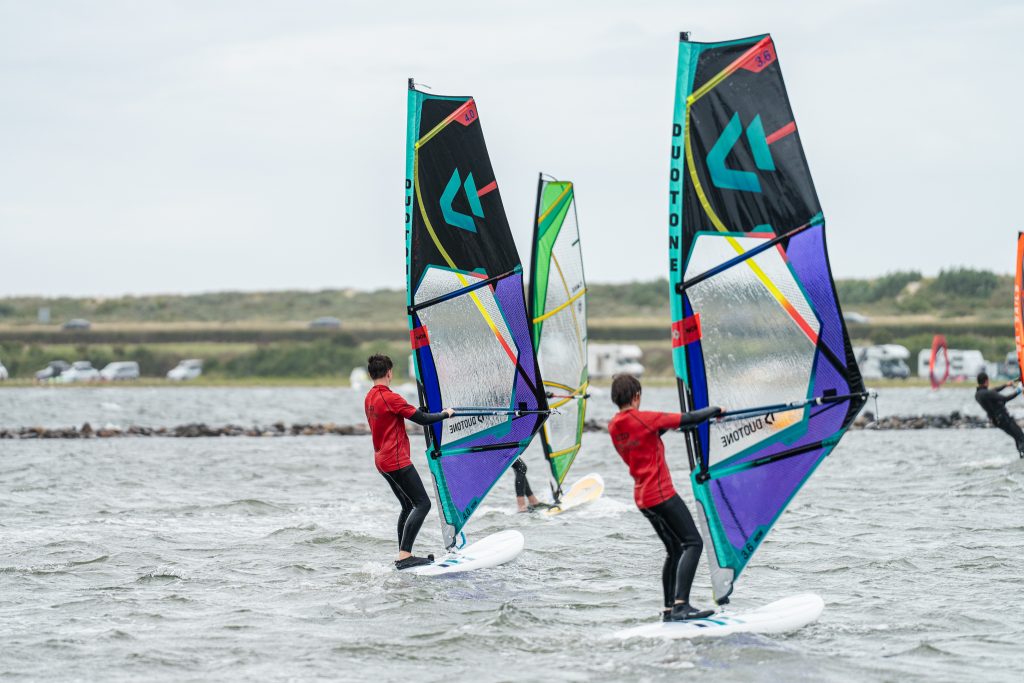 Kinderen leren windsurfen in ondiep water